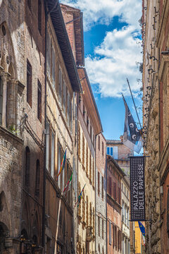Siena, Italy - 23 may 2026: A narrow street in the historic center of Siena, Italy, featuring a vertical sign reading "Palazzo delle Papesse", a well-known Renaissance-style palace and contemporary ar
