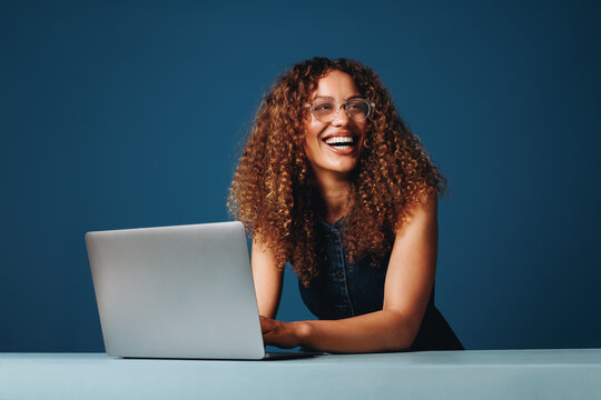 Professional woman works on a laptop in a smiling studio portrait