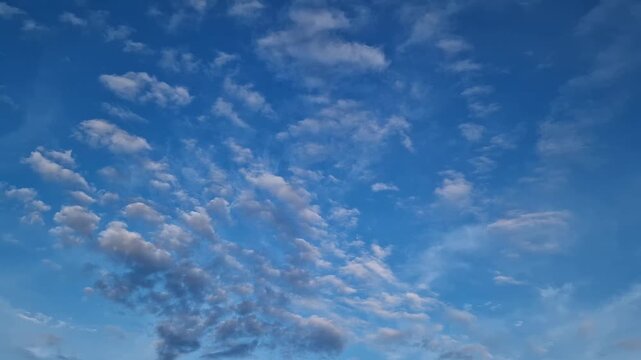 Blue sky covered with small white cumulus clouds, cloudy sky on a bright day, natural background. Picturesque summer day with light white clouds against a background of a rich blue sky