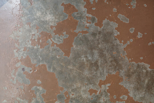 close-up shot of worn and flaking brown lacquer paint over an aged gray concrete surface creating an abstract grunge texture with no people present.