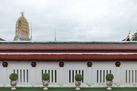 Golden prang tower and tiled roof at Phuttha Chinnarat temple in Phitsanulok, Thailand. 