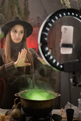 Halloween. Stop right there. witch blogger recording video with smartphone use cauldron prepare poison showing block, say no. Black magic occult female wizard © Andrii Lysenko