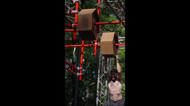 The yound sportsman is navigating an obstacle course consisting of monkey bars