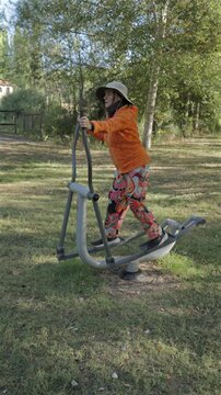Active Woman Exercising on Outdoor Elliptical Trainer in Park