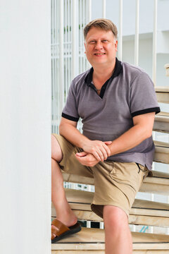 Man sitting steep spiral staircase outside a house, architectural interior design concept.