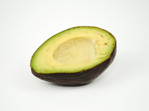 Single half of a ripe seedless avocado showing smooth creamy pale-green flesh with the seed removed, isolated on a clean white background