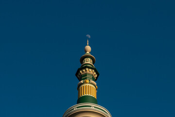 Islamic mosque minaret spire top with crescent moon in clear blue sky background © Runazeru