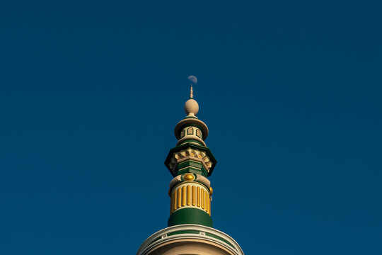 Islamic mosque minaret spire top with crescent moon in clear blue sky background