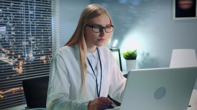 A professional psychologist with glasses and blonde hair conducts an online therapy session using a laptop in a bright, modern office with city skyscrapers visible through the window.