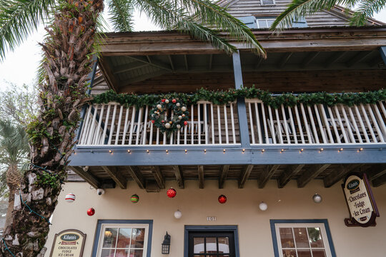 St. Augustine,FL,USA - Dec.30.2024: A Christmas wreath and green garland decorate the balcony of a historic wooden building in St. Augustine, Florida. Colorful ornaments and string lights hang above a