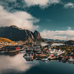 High angle panoramic view of Reine village with red cabins and bridges surrounded by fjord and mountains in Lofoten Norway © Quality by Simon