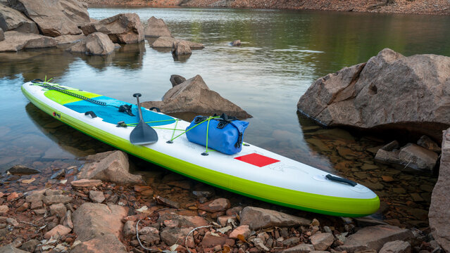 inflatable stand up paddleboard on a rocky shore of mountain lake - Horsetooth Reservoir in northern Colorado in fall scenery