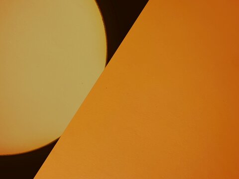 An abstract composition featuring circular shapes and angular planes in dark orange against a dark background.