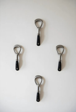 Hospitality and catering service, four metal bottle openers arranged in a diamond pattern on a clean white wall for bar and restaurant equipment