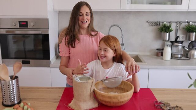 Zoom in video of mother and daughter sifting flour while baking cookies