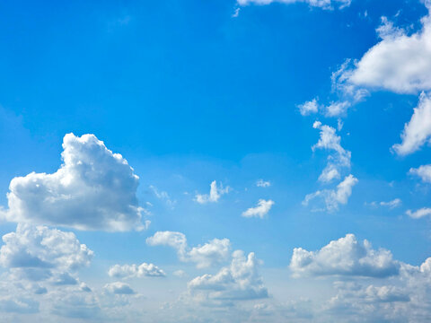 A high resolution photo showcasing a vibrant blue sky filled with scattered white cumulus clouds. Clouds receding into the distance. The natural daylight highlights the soft textures of the clouds