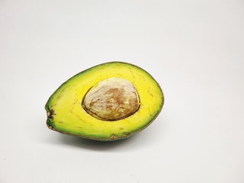 Sliced green avocado showing pit and yellow flesh on plain white background