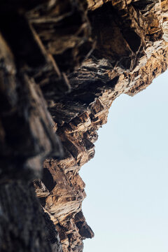 Detailed texture of rugged cliff rock formation against clear sky in Portugal