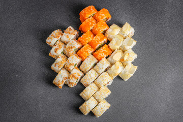 Assorted sushi rolls arranged in colorful diagonal rows with orange, white, and pale toppings on a dark textured background, overhead food presentation © Надія Коваль