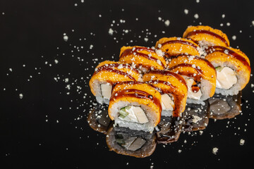 Glazed sushi rolls with creamy filling and sesame garnish arranged on reflective black surface, colorful Japanese cuisine closeup with dramatic splashes and food styling © Надія Коваль