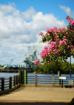 The Riverwalk in downtown Wilmington NC with the Cape Fear River and battleship North Carolina in the background
