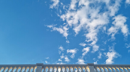White architectural balustrade beneath blue sky with scattered clouds. Architectural photography with copy space © Natalia_SL