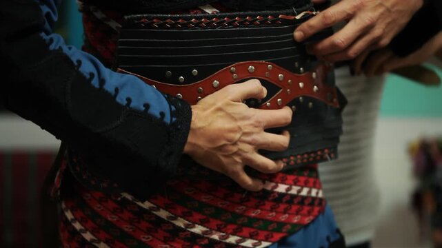 Close up shot of dancer putting on traditional leather cartridge belt silahlik for Turkish Zeybek folk costume