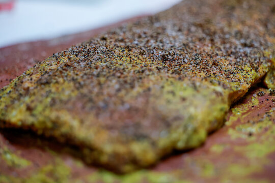 Barbecue pork ribs smothered in mustard, black pepper, salt, and garlic powder resting on butcher paper before going in the pellet grill smoker to cook.