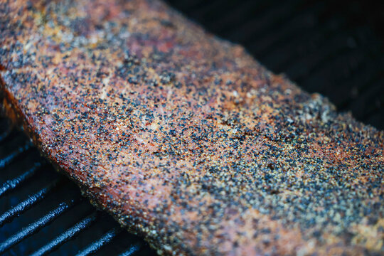 Barbecue pork ribs seasoned with salt, pepper, garlic for a crunchy bark. The bbq meat is cooking on a pellet grill smoker. 