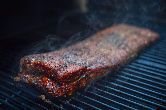Pork ribs on a barbecue pellet grill smoker with salt and pepper seasoning. The bbq meat is tender and delicious. 