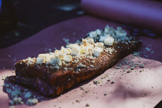 Cooked pork ribs topped with butter cubes and brown sugar on butcher paper, ready to be wrapped after smoking.