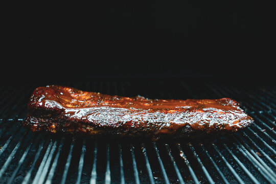 Barbecue pork ribs smothered in homemade bbq sauce smoking on a pellet grill smoker for dinner. 