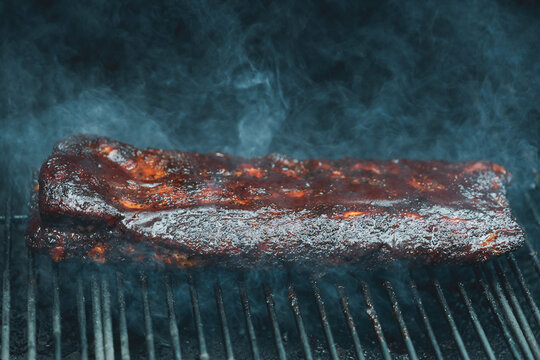Barbecue pork ribs smothered in homemade bbq sauce smoking on a pellet grill smoker for dinner. 