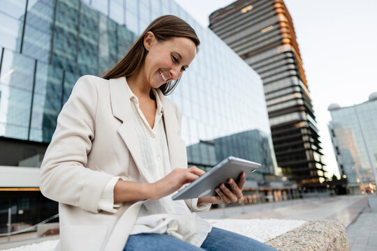 Professional woman smiling using digital tablet in urban setting