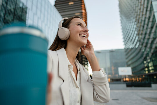 Happy businesswoman listening to music in urban setting
