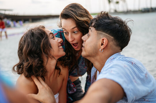 Happy diverse friends bonding over laughter and secrets during a joyful summer evening at the coast