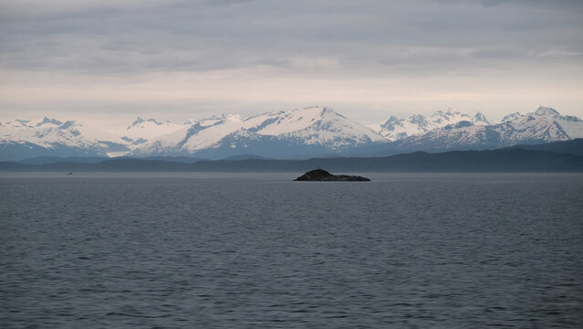 Breathtaking Alaska mountain glacier range view seen from outdoor deck of cruise ship liner sailing the Inside Passage transit with spectacular landscape scenery during sunset