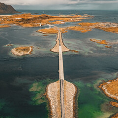 Vertical aerial view of narrow coastal road and bridges connecting rocky islands in fjord in Lofoten Norway © Quality by Simon