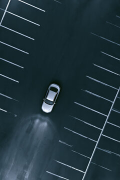 Minimalist lone car in empty neon parking lot serene peaceful monochromatic B&W drone