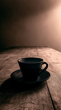 Minimalist lone dark coffee cup on wooden table with moody low key sepia lighting