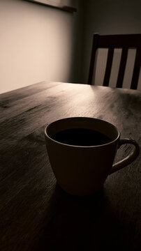 Minimalist lone dark coffee cup on wooden table with moody low key sepia lighting
