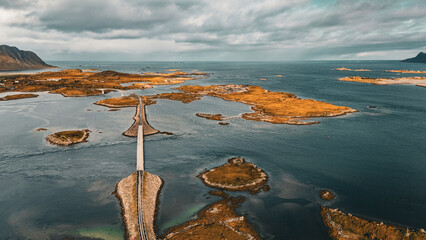 Panoramic aerial view of coastal road and bridges connecting rocky islands in fjord under cloudy sky in Lofoten Norway © Quality by Simon