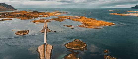 Panoramic aerial view of coastal road and bridges connecting rocky islands in fjord under cloudy sky in Lofoten Norway © Quality by Simon