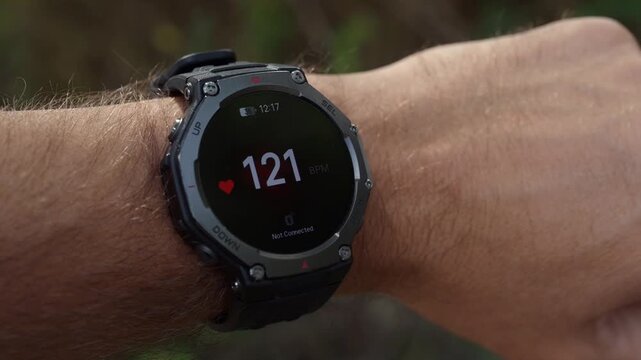 Smartwatch displaying heart rate pulse measuring 121 bpm on a man's wrist