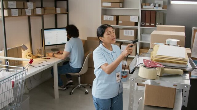 Hispanic young woman scanning packages with barcode reader and digital tablet in warehouse. Footage fits e-commerce logistics, online retail distribution, supply chain management videos