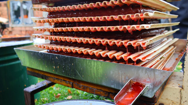 Freshly pressed apple and chokeberry juice flowing from a traditional fruit press into a collection bucket, symbolizing healthy natural beverage production and autumn harvest