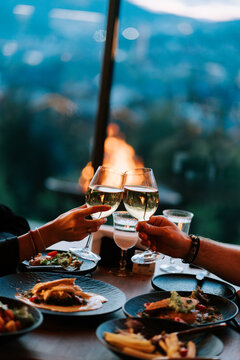 Clinking wine glasses at a mountain-view sunset dinner