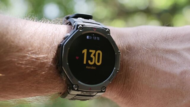 Smartwatch displaying aerobic zone heart rate 130 bpm on a male wrist