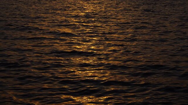 Tranquil sea surface under sunrays during golden hour