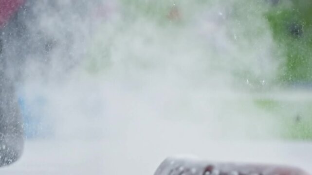 Climber's hands pouring magnesium carbonate chalk, releasing a white cloud of powder in slow motion